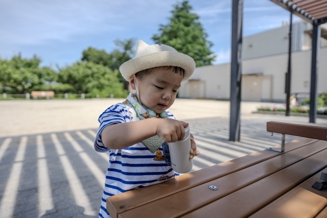 ベンチで水筒を持っている男の子